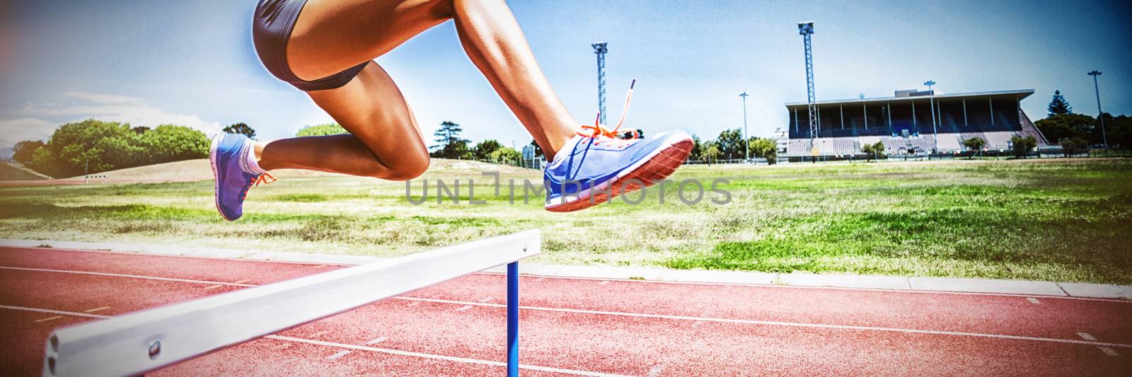 Female athlete jumping above the hurdle by Wavebreakmedia