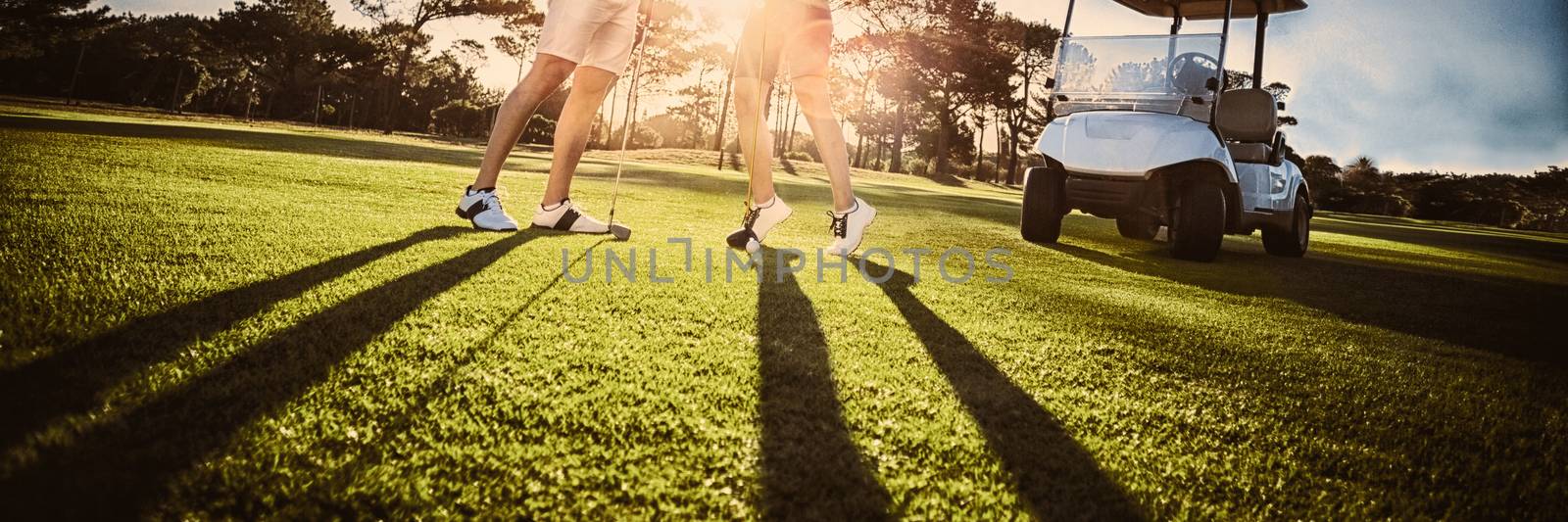 Happy golf player couple giving high five while standing on field