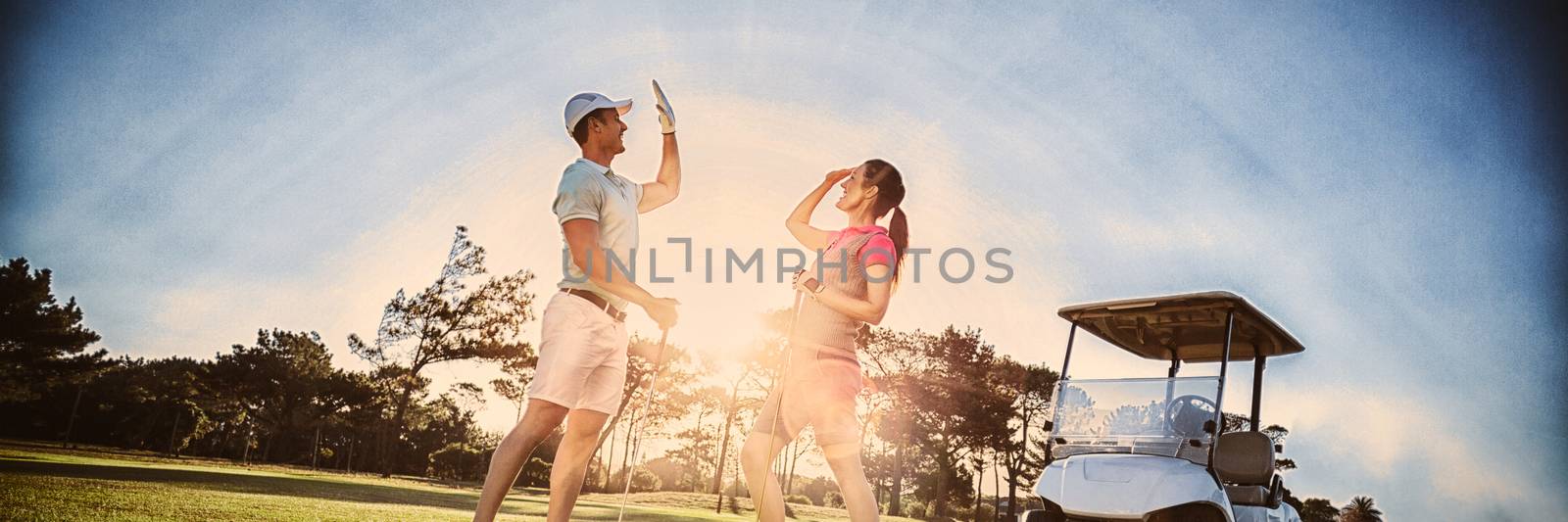 Full length of golf player couple giving high five by Wavebreakmedia