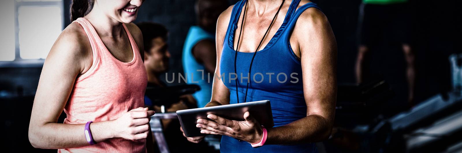 Smiling friends with digital tablet in gym by Wavebreakmedia