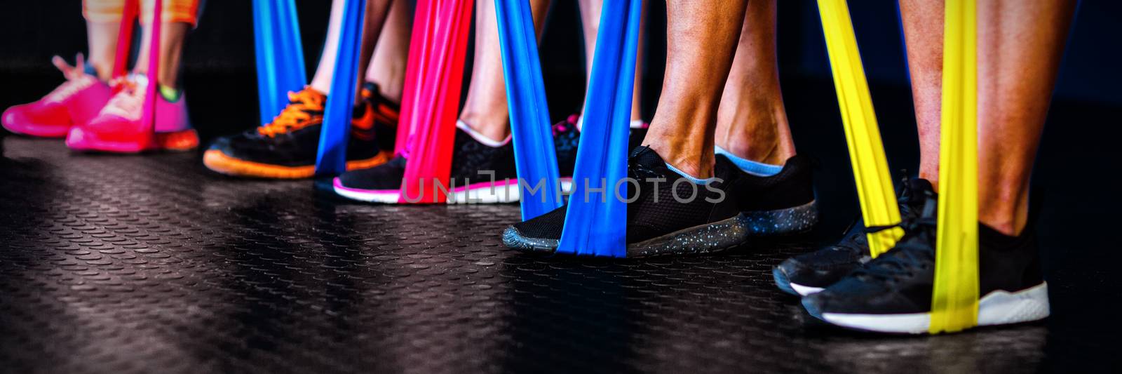 Low section of athletes exercising with resistance band in gym