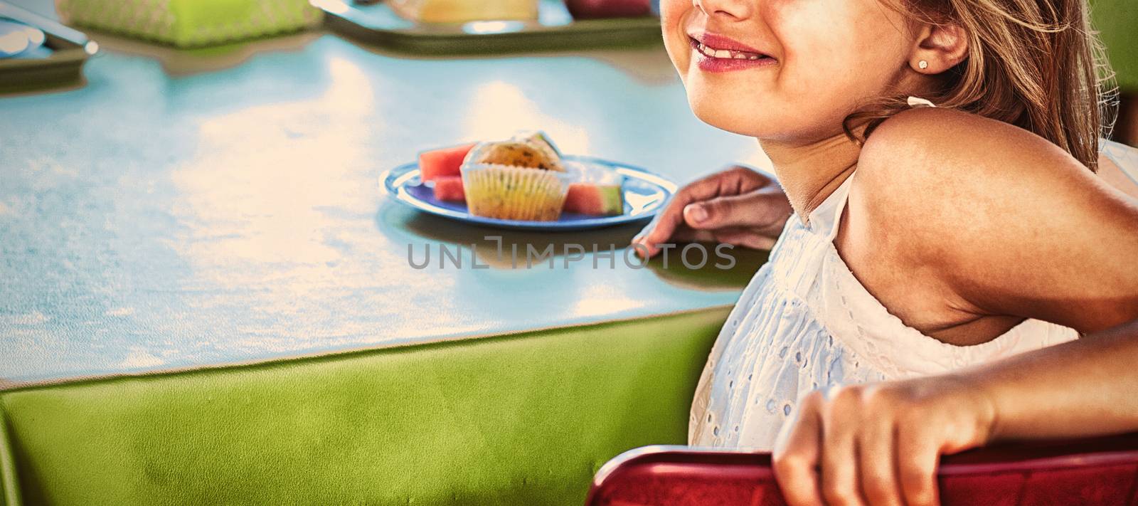 Portrait of cute girl with classmates having meal in canteen