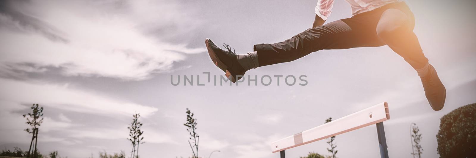 Businessman jumping a hurdle while running by Wavebreakmedia