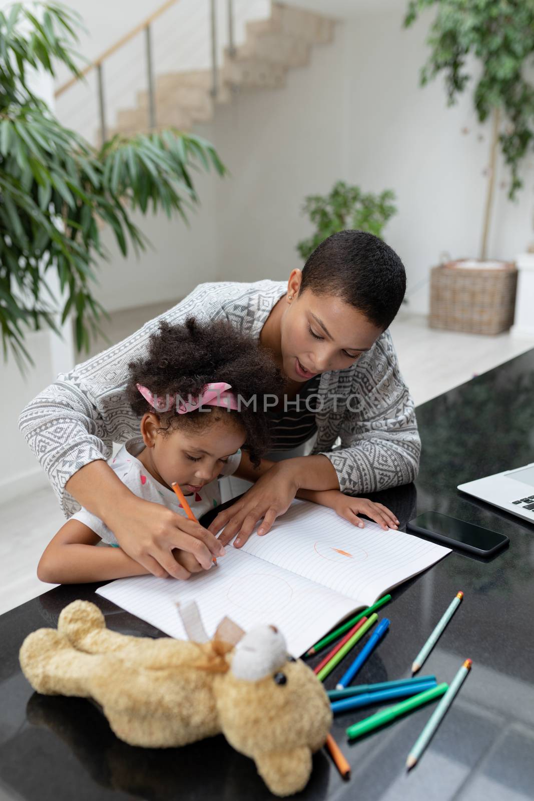 Mother helping her daughter with her homework on a table by Wavebreakmedia