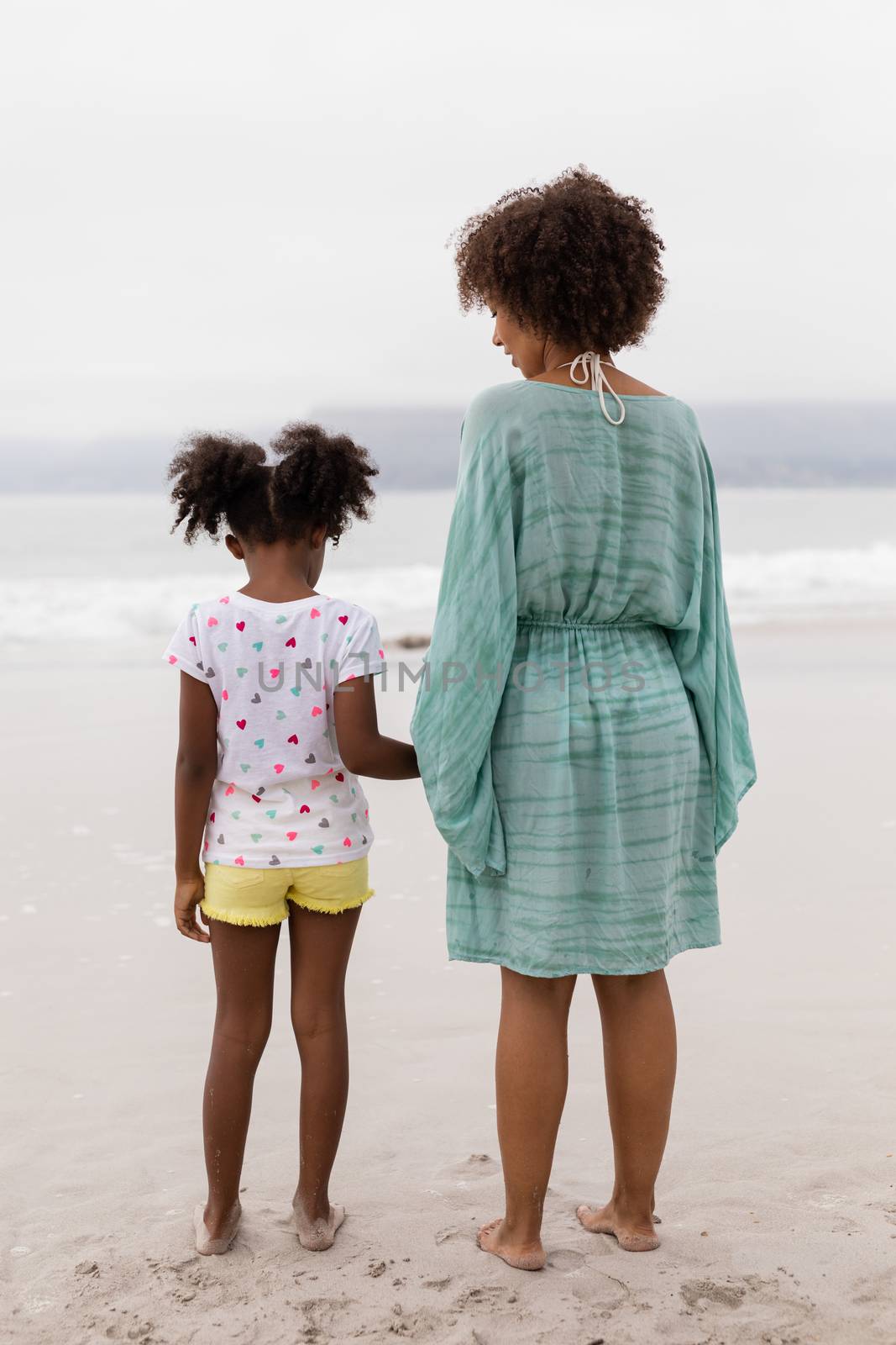 Mother and daughter standing together on the beach by Wavebreakmedia