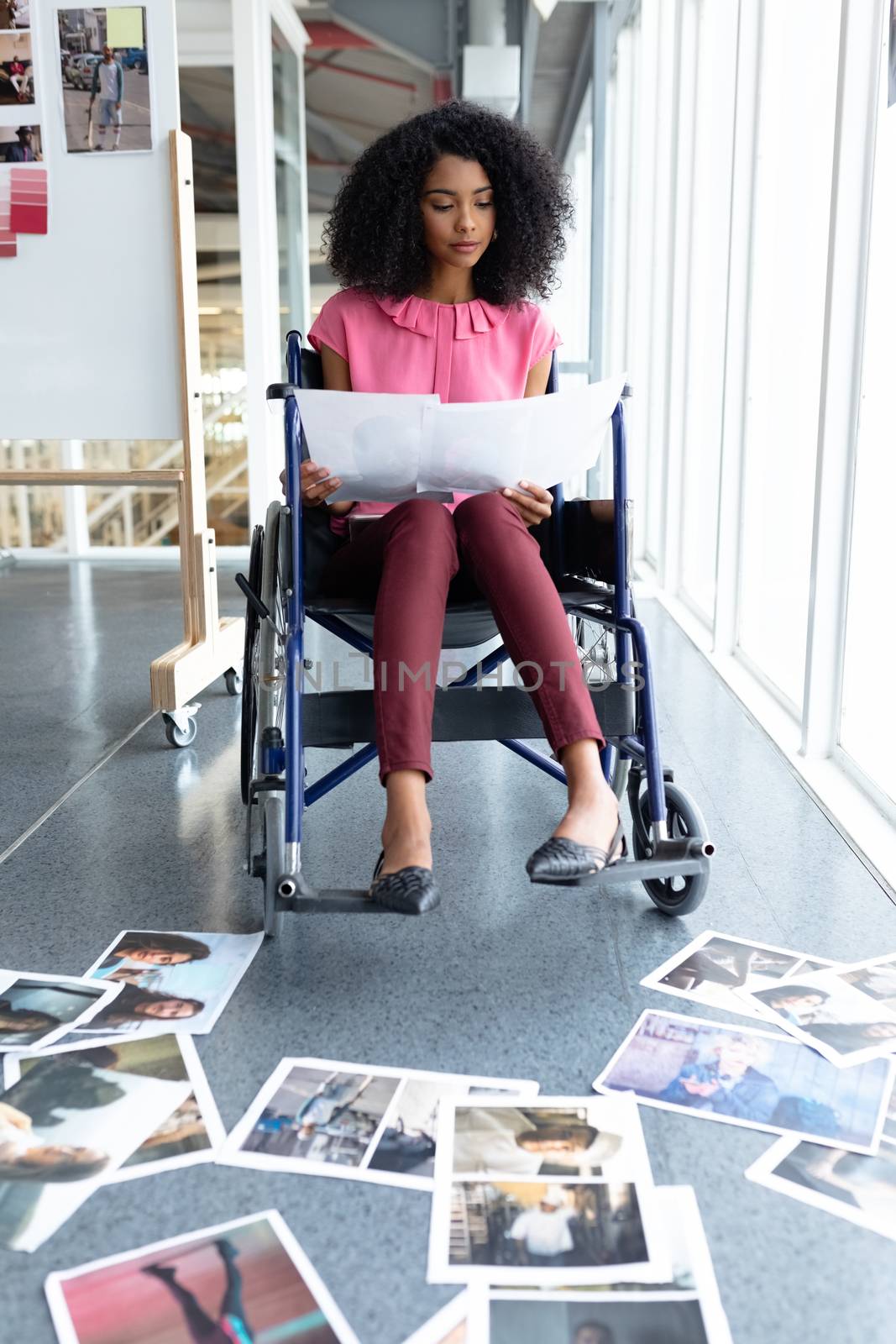 Disabled graphic designers looking at photographs in office by Wavebreakmedia