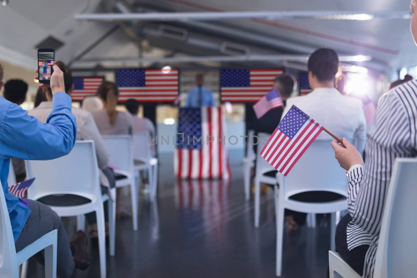 Front view of diverse business people waving an American flag in business seminar. International diverse corporate business partnership concept