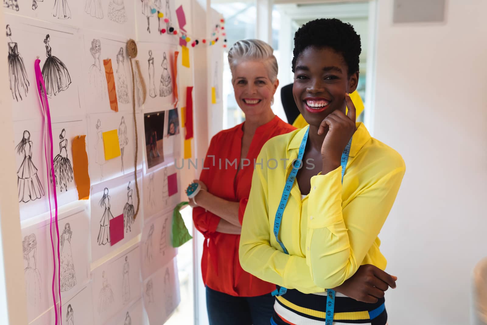 Female fashion designers standing together with arms crossed in design studio by Wavebreakmedia