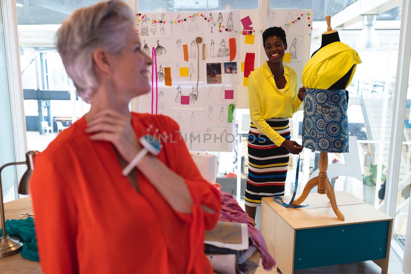 Front view of diverse female fashion designers interacting with each other in design studio. This is a casual creative start-up business office for a diverse team