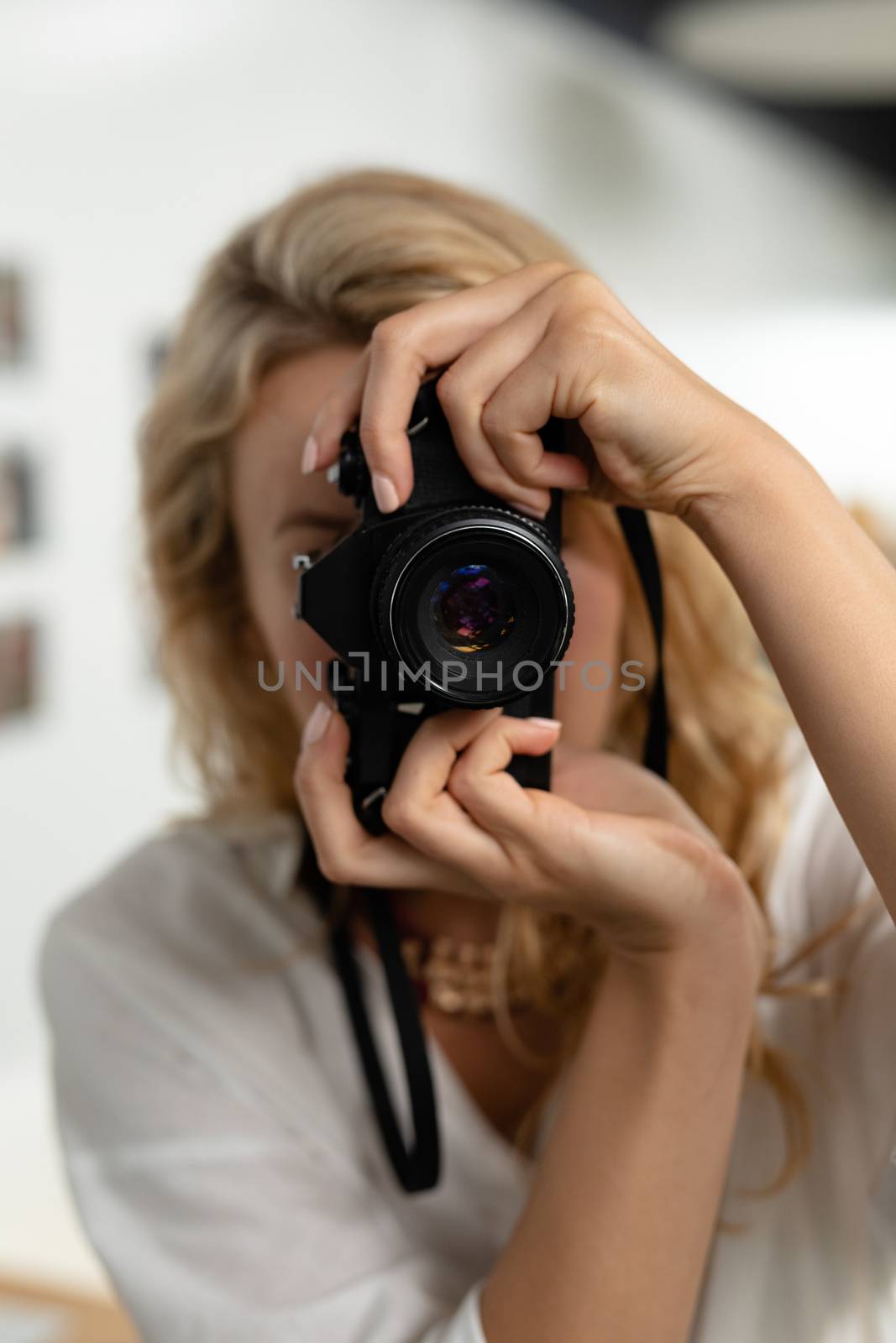 Front view of beautiful Caucasian female graphic designer clicking pictures with digital camera in office. This is a casual creative start-up business office for a diverse team