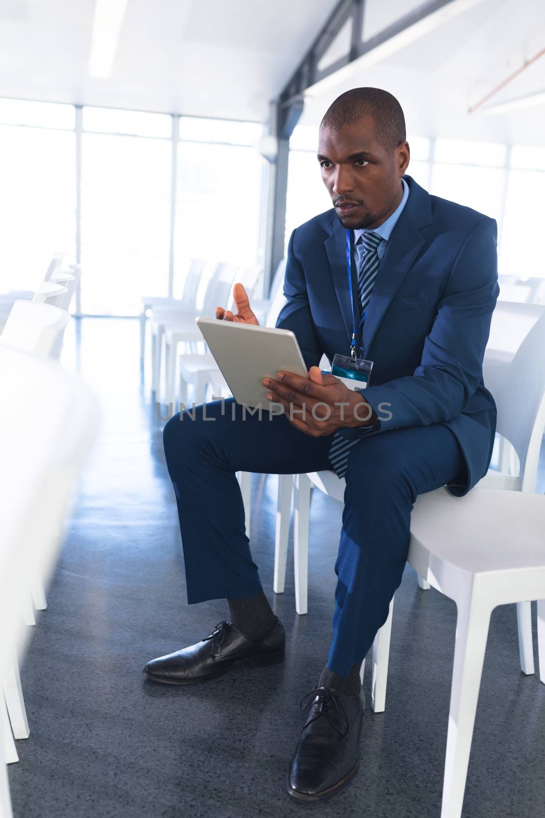 Front view of African-american Male speaker practicing his speech on digital tablet in business seminar at conference room. International diverse corporate business partnership concept