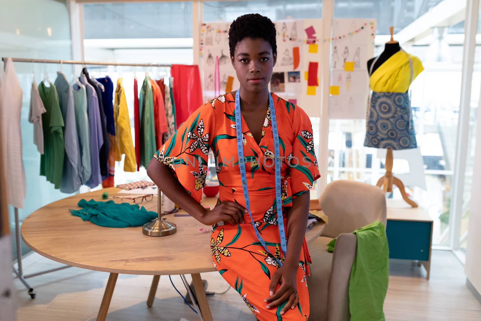 Female fashion designer sitting with hand on hip in design studio by Wavebreakmedia