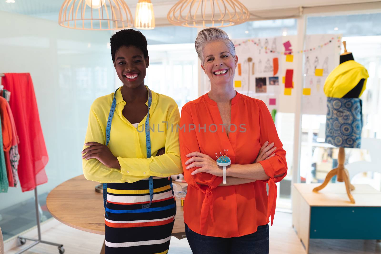 Portrait of diverse female fashion designers standing with arms crossed in design studio. This is a casual creative start-up business office for a diverse team
