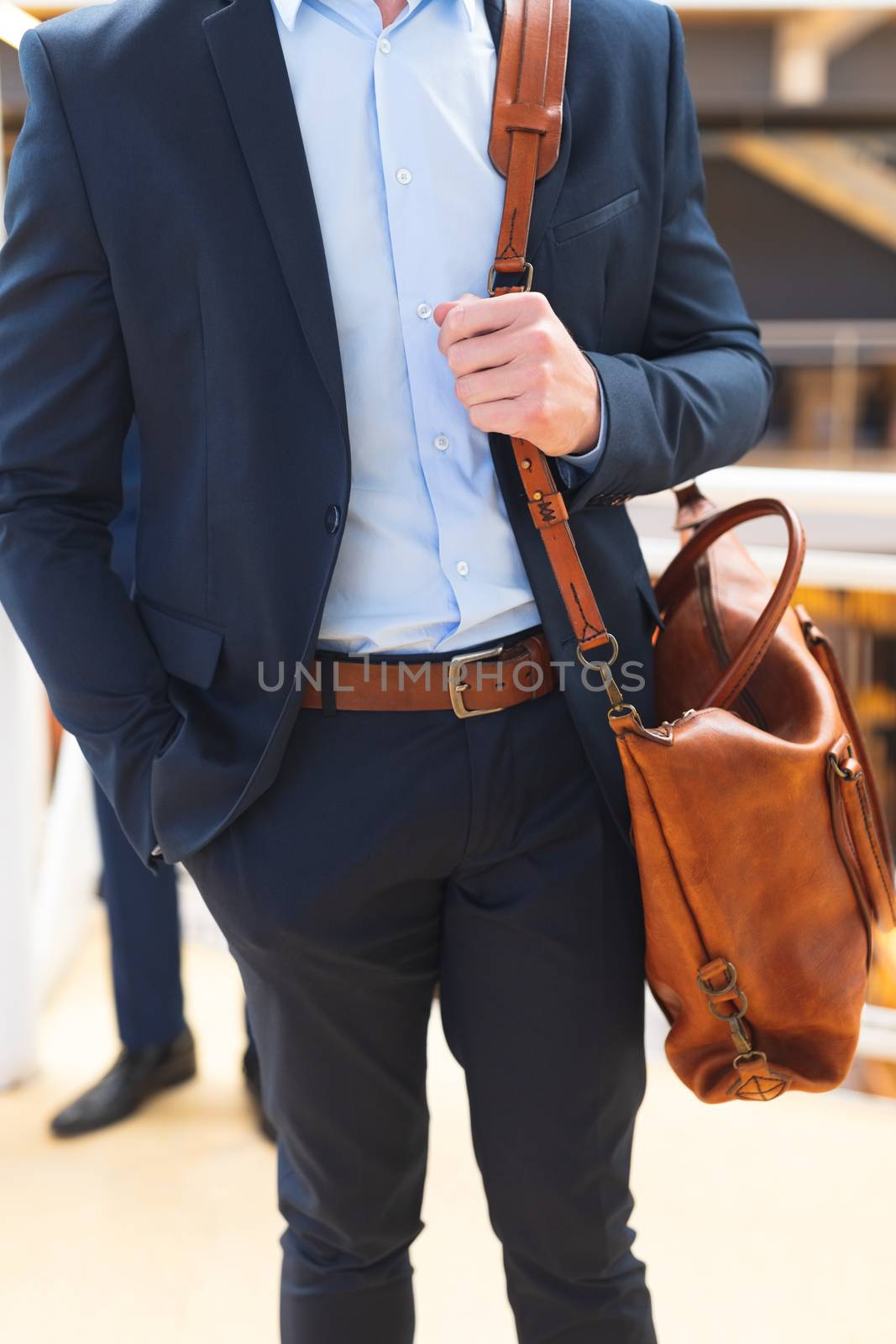 Mid section of Caucasian Businessman standing with office bag in the corridor at office. International diverse corporate business partnership concept