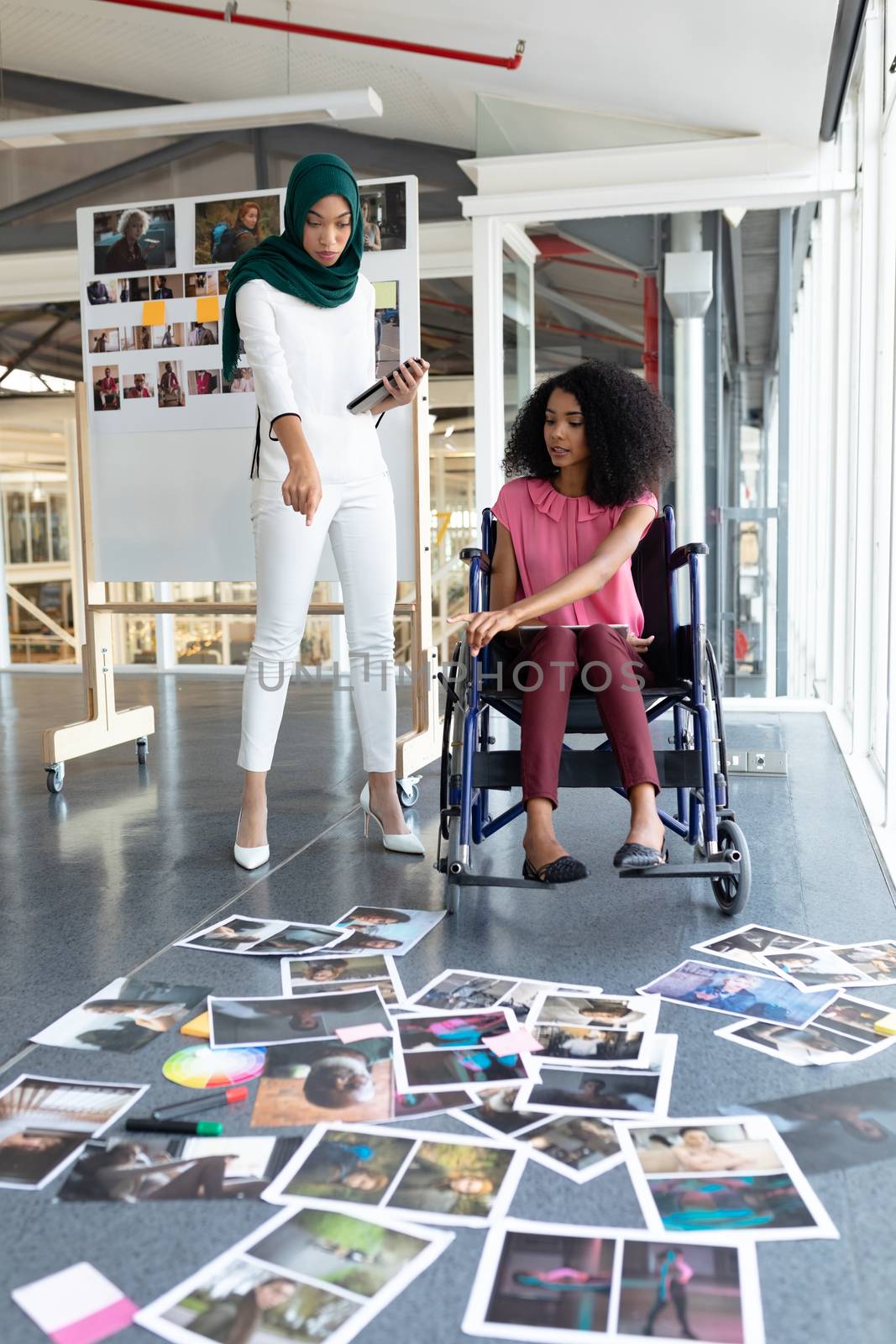 Female graphic designers discussing on photographs in office by Wavebreakmedia