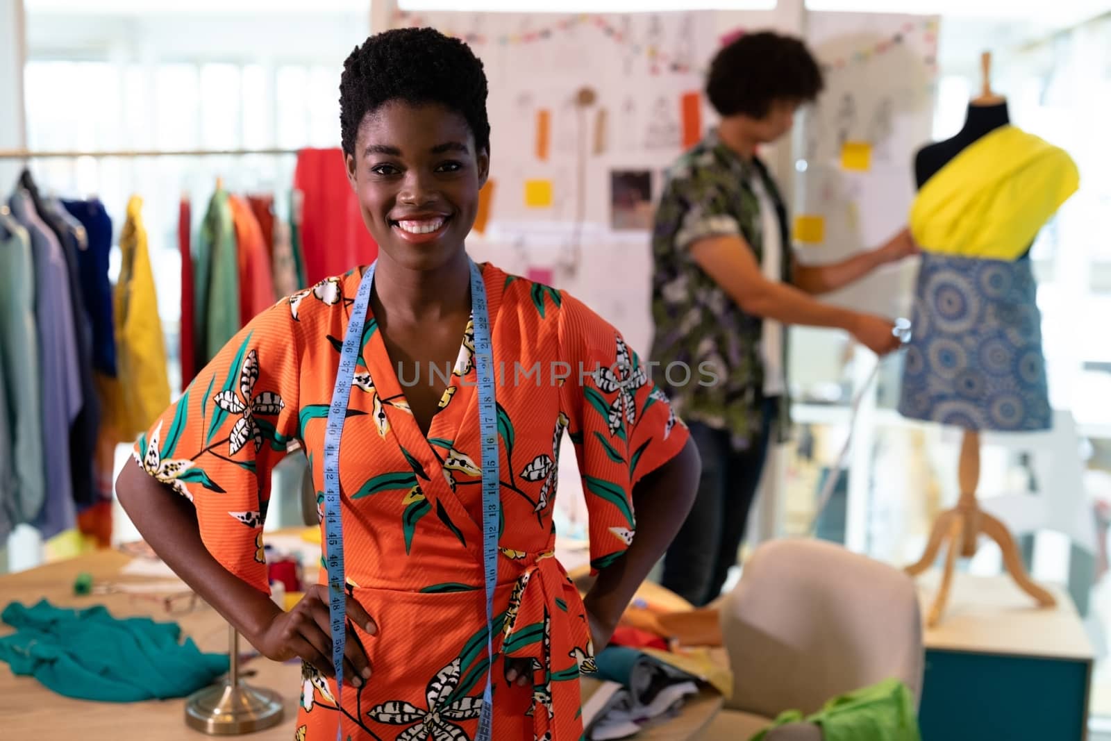 Female fashion designer standing with hands on hip in design studio by Wavebreakmedia