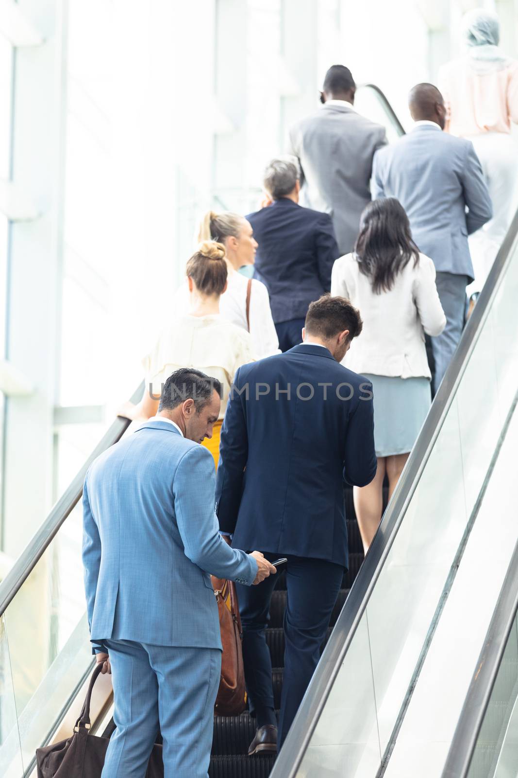 Rear view of diverse business people on escalator in modern office