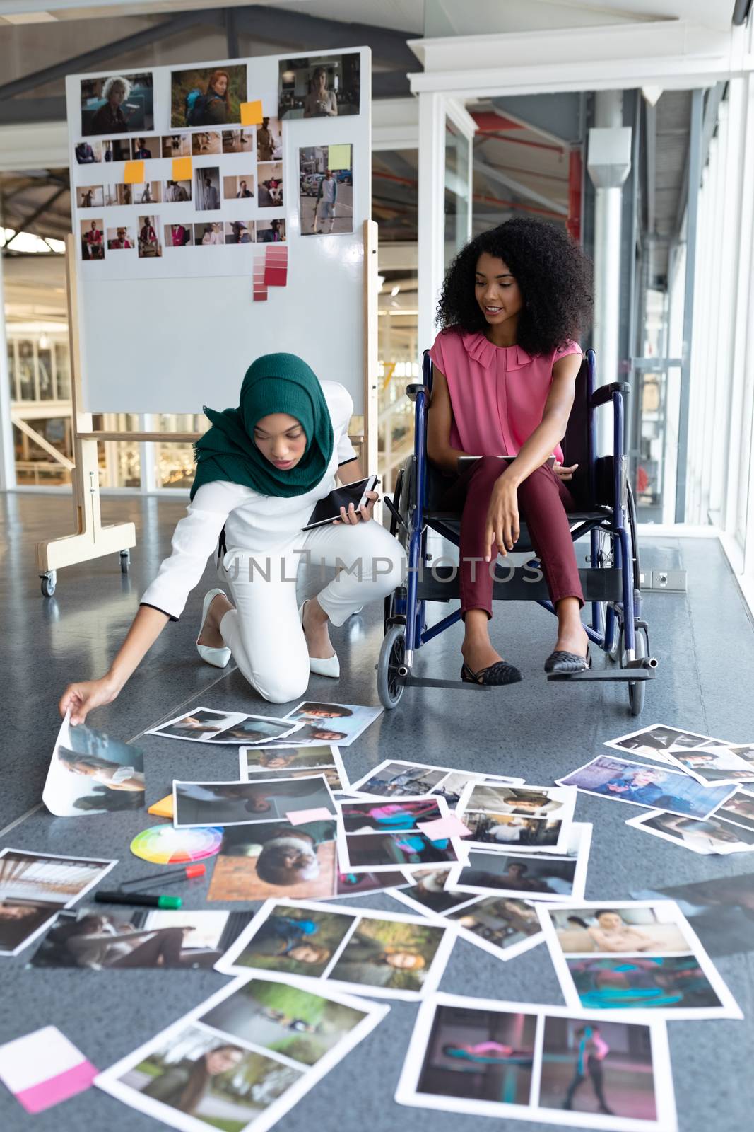 Female graphic designers looking at photographs in office by Wavebreakmedia