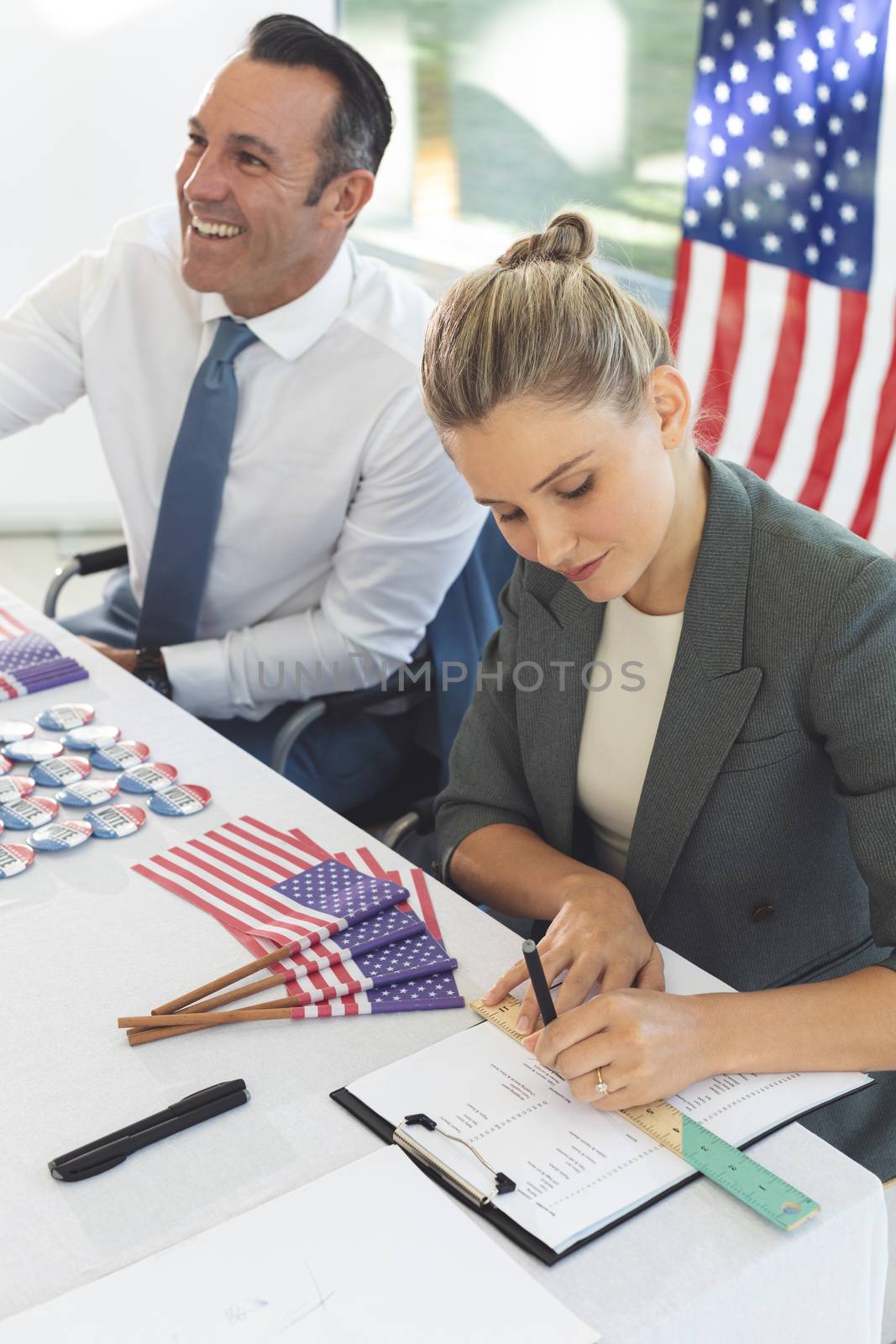 Front view of diverse business people sat next to desk, smiling and writing