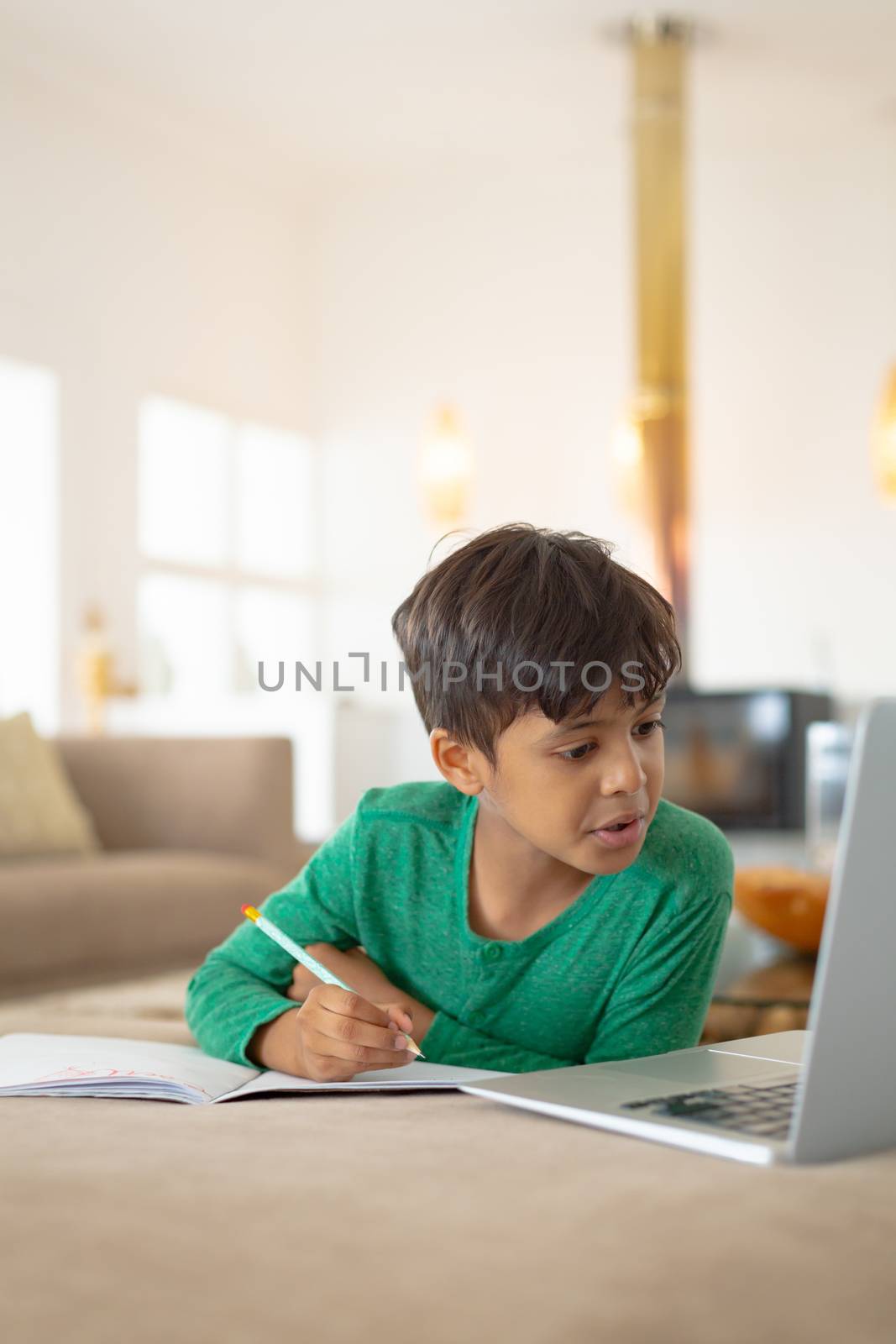 Boy using laptop while drawing a sketch on book at home by Wavebreakmedia