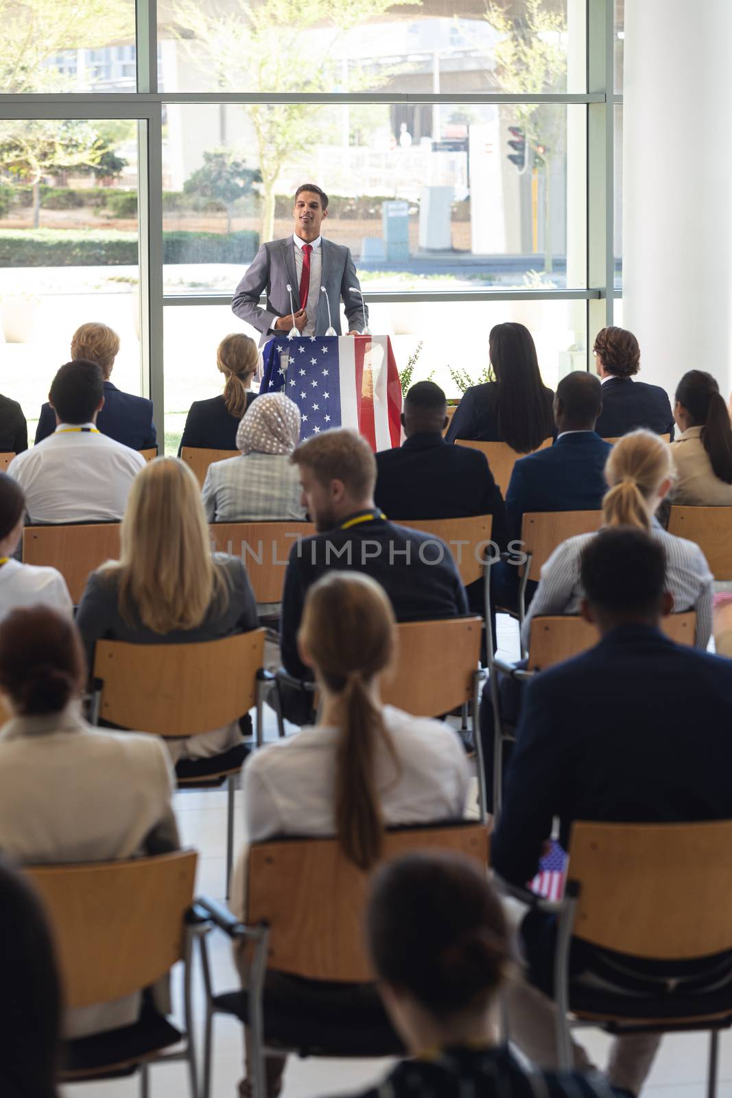 Front view of young Caucasian businessman doing speech in conference room