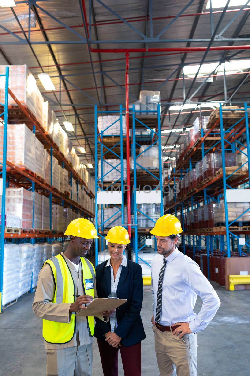 Front view of diverse mature staffs working together on clipboard in warehouse. This is a freight transportation and distribution warehouse. Industrial and industrial workers concept