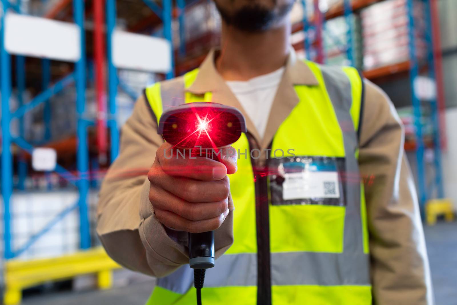 Mid section of mature Asian male worker showing barcode scanner on camera in warehouse. This is a freight transportation and distribution warehouse. Industrial and industrial workers concept