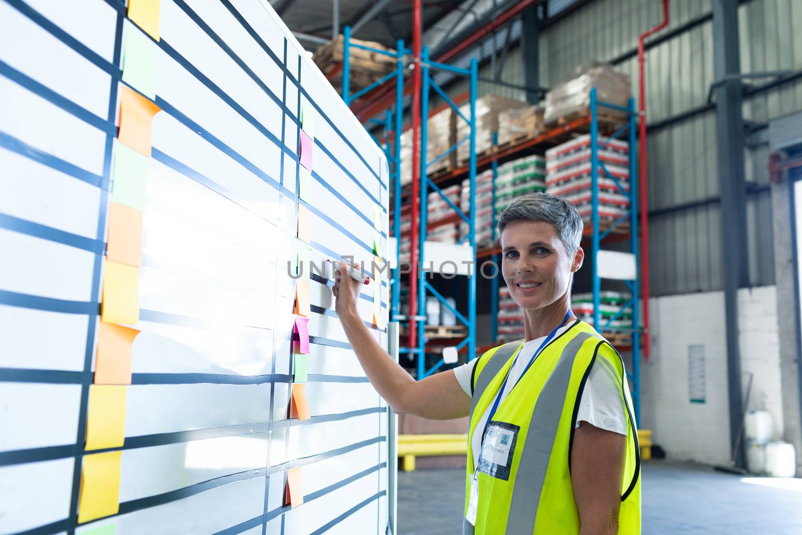 Female staff writing on whiteboard in warehouse by Wavebreakmedia