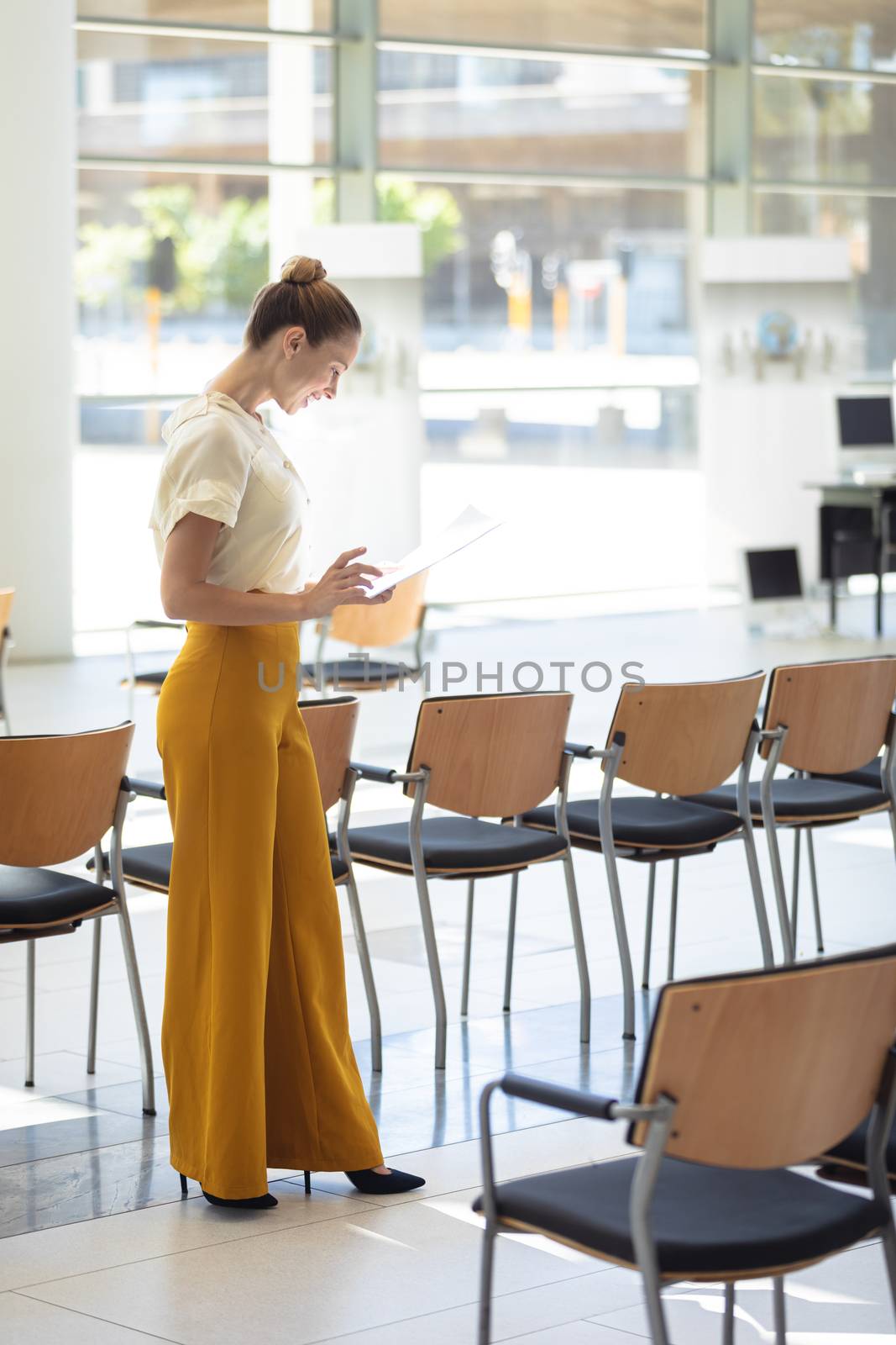 Caucasian female executive looking at documents while standing in empty conference room by Wavebreakmedia