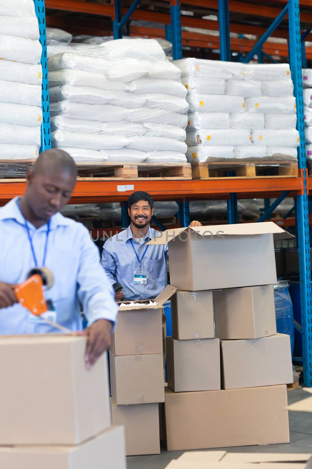 Male staff looking at camera while checking stock in warehouse by Wavebreakmedia