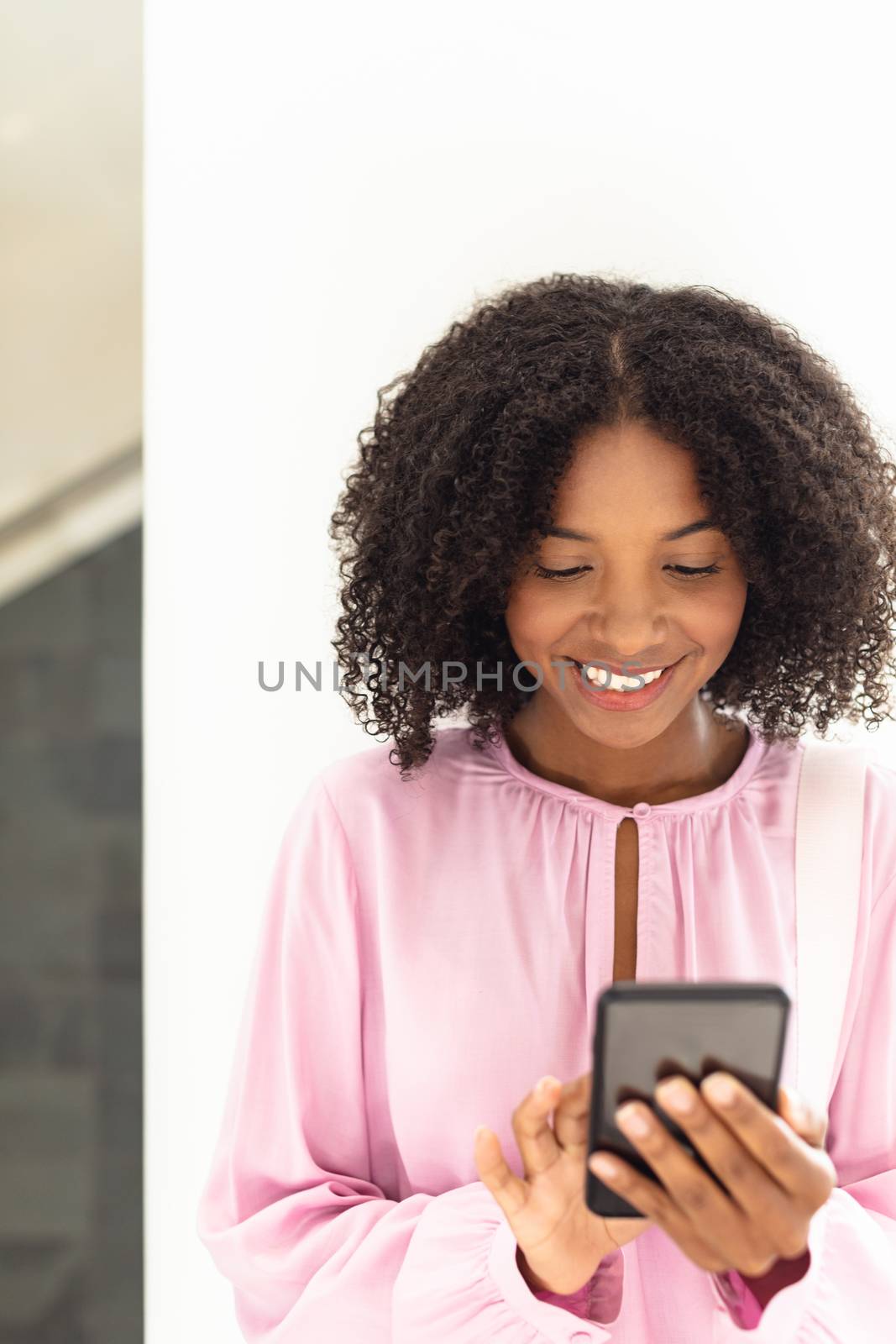 Young pretty African-american employee looking her phone by Wavebreakmedia