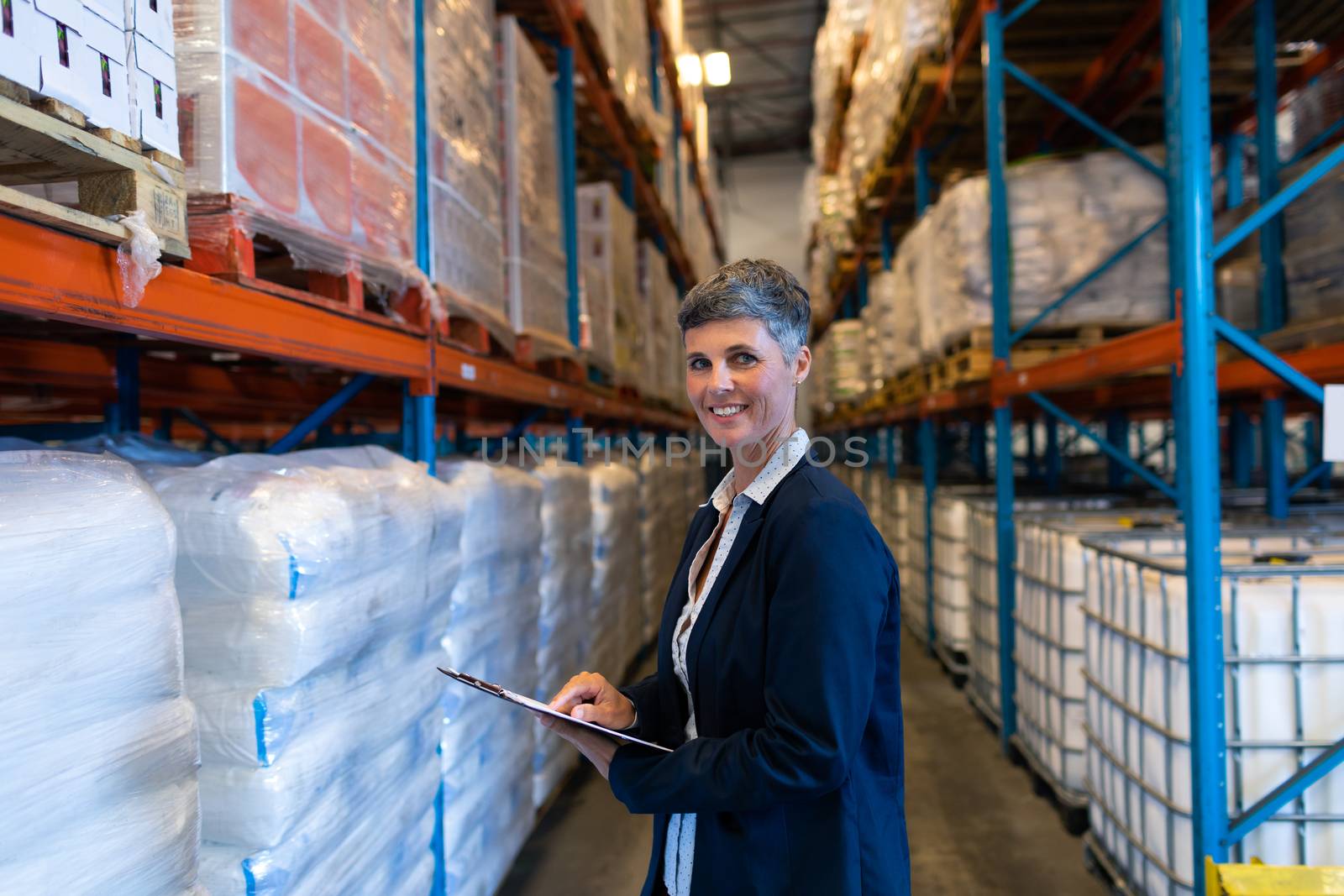 Female manager looking at camera while working in warehouse by Wavebreakmedia