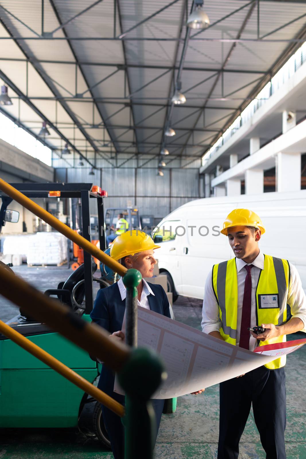 Front view of Caucasian female manager and Caucasian male supervisor discussing over inventory chart in warehouse. This is a freight transportation and distribution warehouse. Industrial and industrial workers concept