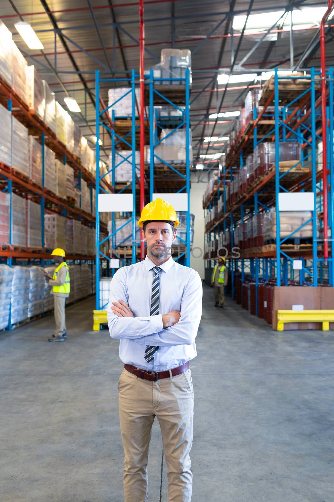 Male supervisor standing with arms crossed and looking at camera in warehouse by Wavebreakmedia