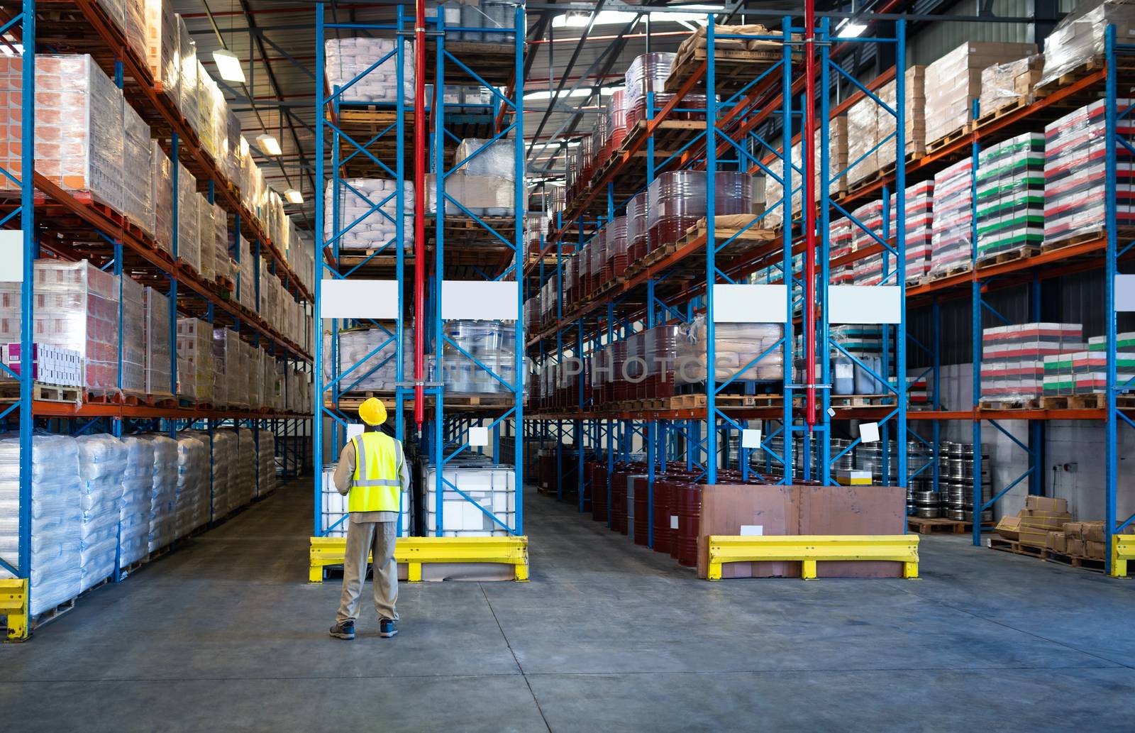 Rear view of African-american male worker working in warehouse. This is a freight transportation and distribution warehouse. Industrial and industrial workers concept