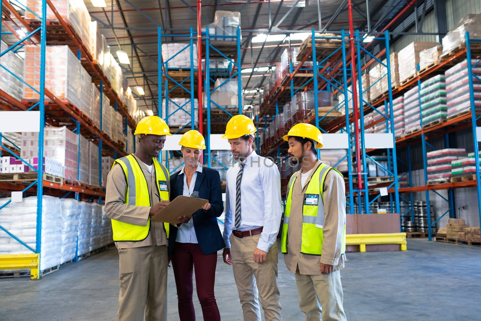 Front view of diverse staffs working together on clipboard in warehouse. This is a freight transportation and distribution warehouse. Industrial and industrial workers concept