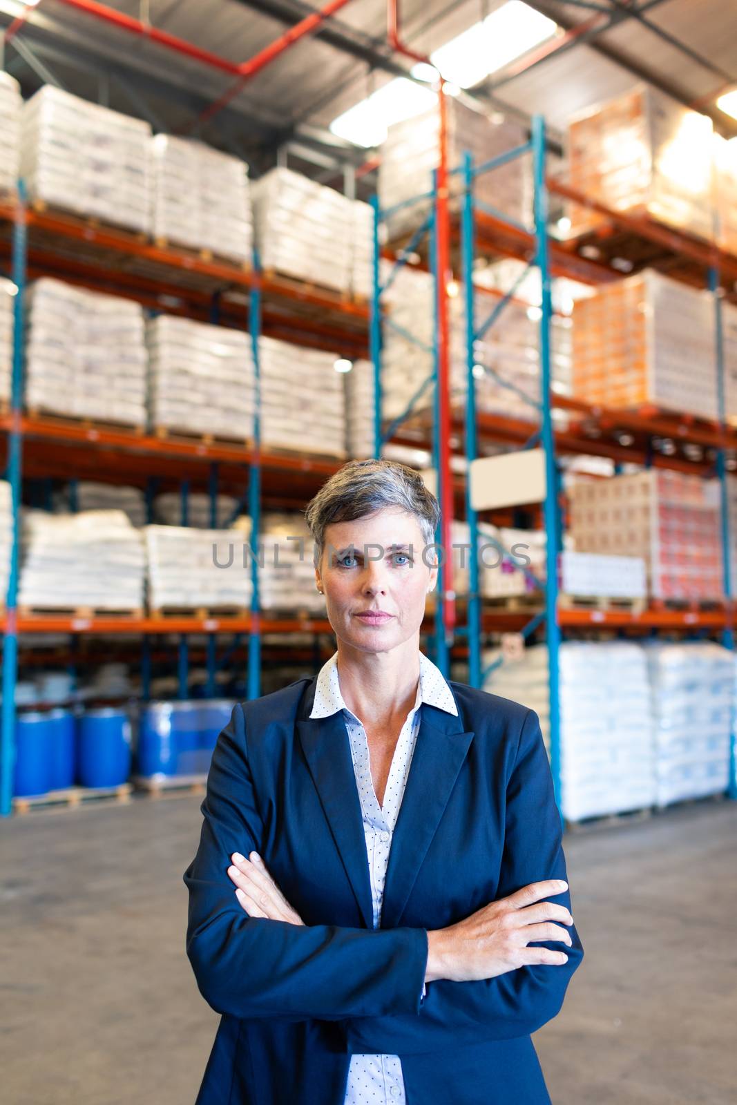 Female manager standing with arm crossed and looking at camera in warehouse by Wavebreakmedia