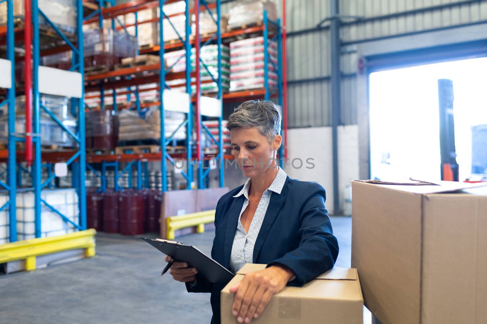 Female manager checking stocks on clipboard in warehouse by Wavebreakmedia