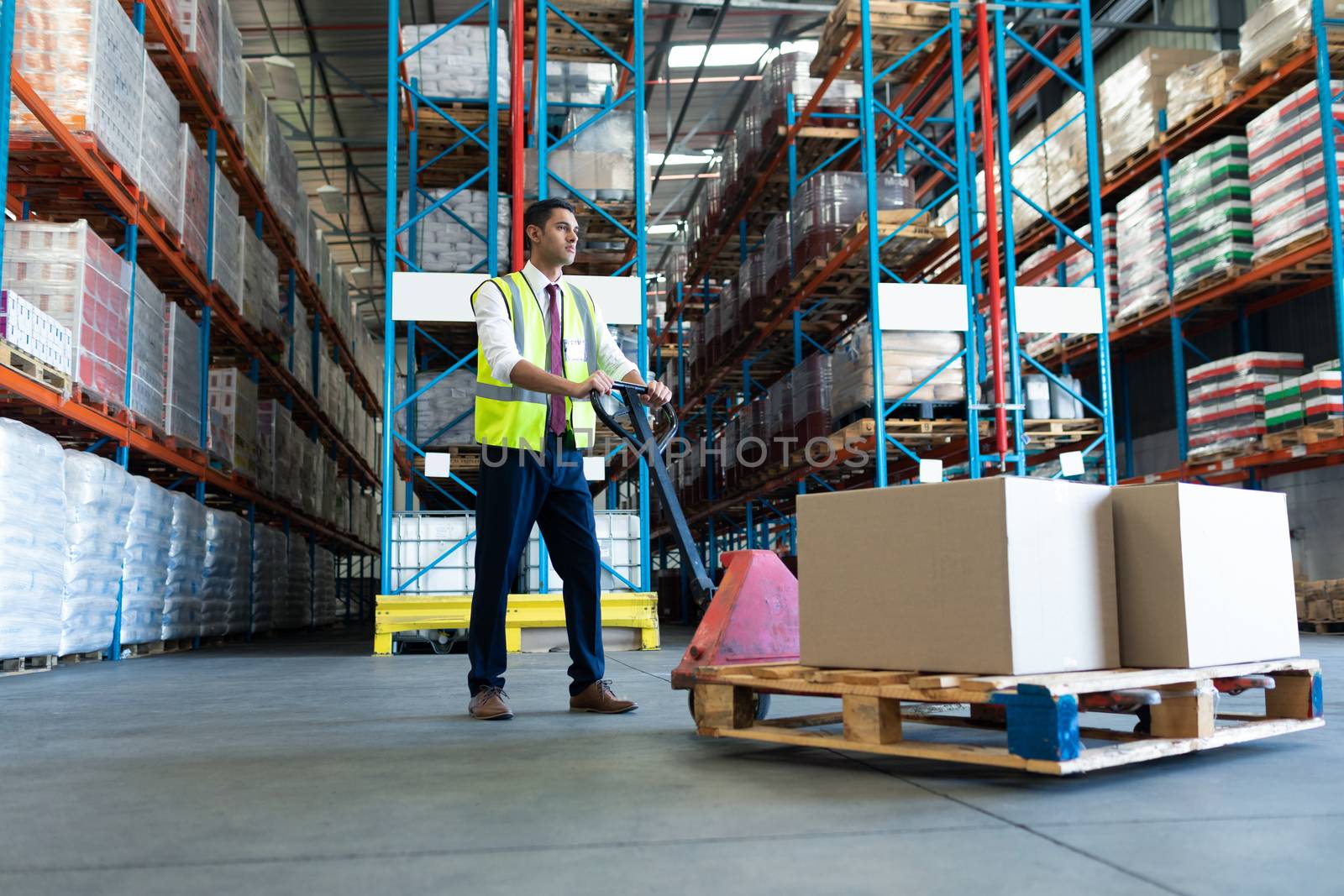 Side view of Caucasian male staff using pallet jack in warehouse. This is a freight transportation and distribution warehouse. Industrial and industrial workers concept