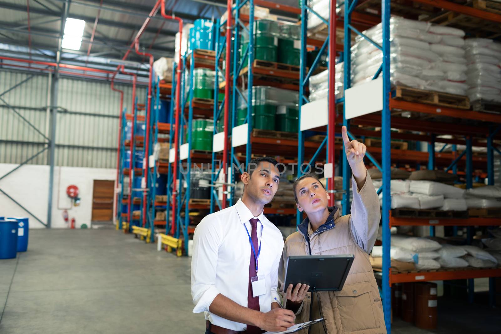 Front view of Caucasian warehouse staffs discussing over digital tablet in warehouse. This is a freight transportation and distribution warehouse. Industrial and industrial workers concept