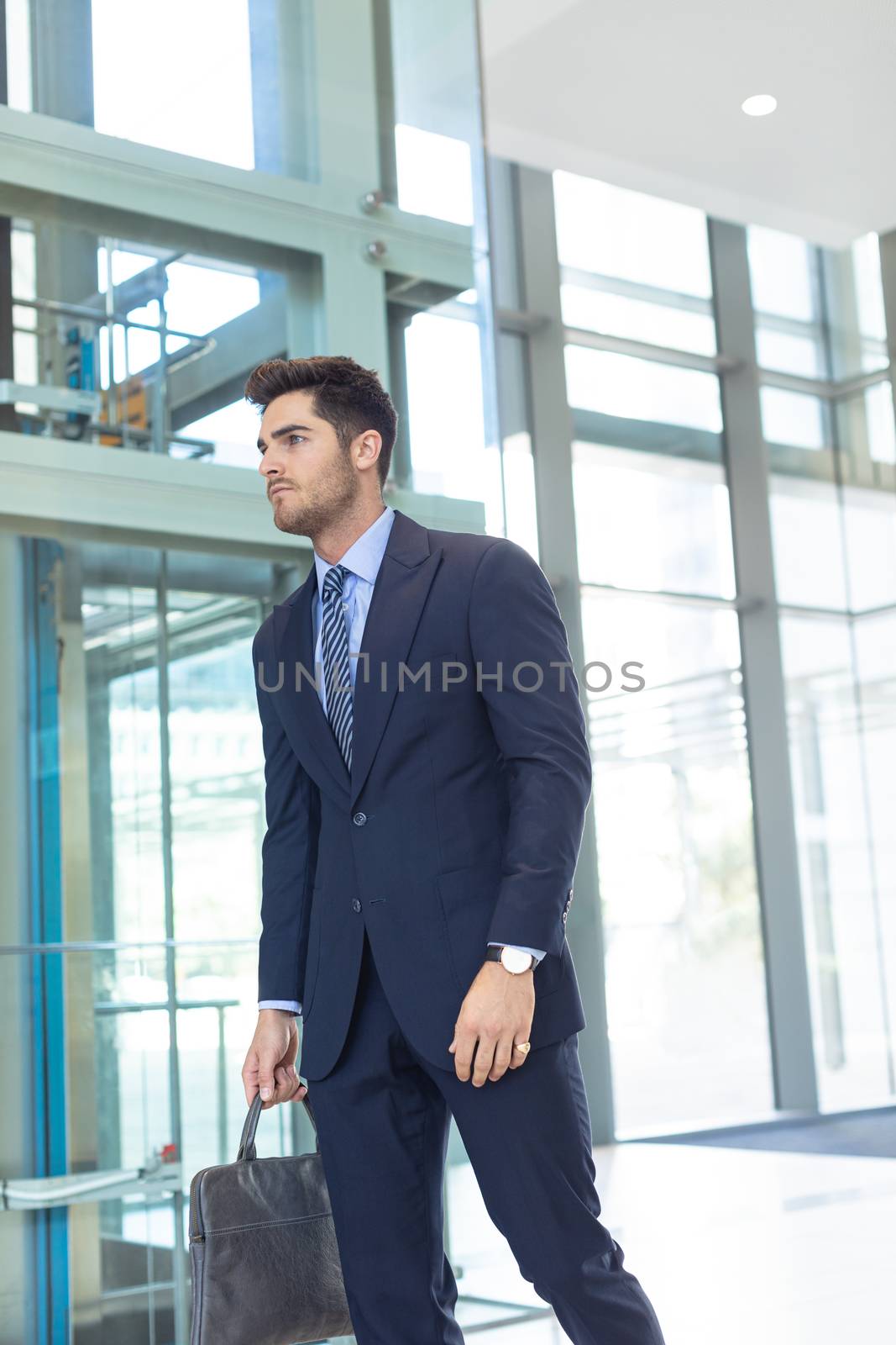 Low angle view of young Caucasian businessman smiling at camera while standing in modern office