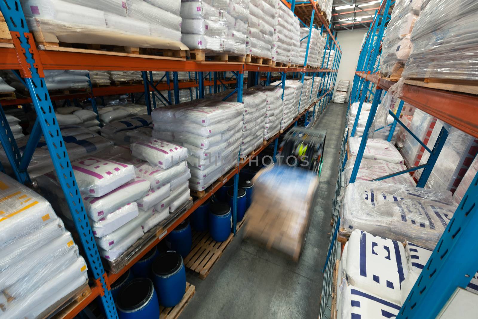 High angle view of African-american male worker driving forklift in warehouse. This is a freight transportation and distribution warehouse. Industrial and industrial workers concept