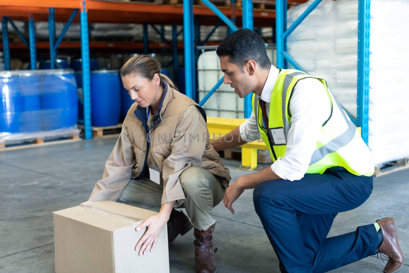 Side view of Young Caucasian male staff giving training to female staff in warehouse. This is a freight transportation and distribution warehouse. Industrial and industrial workers concept