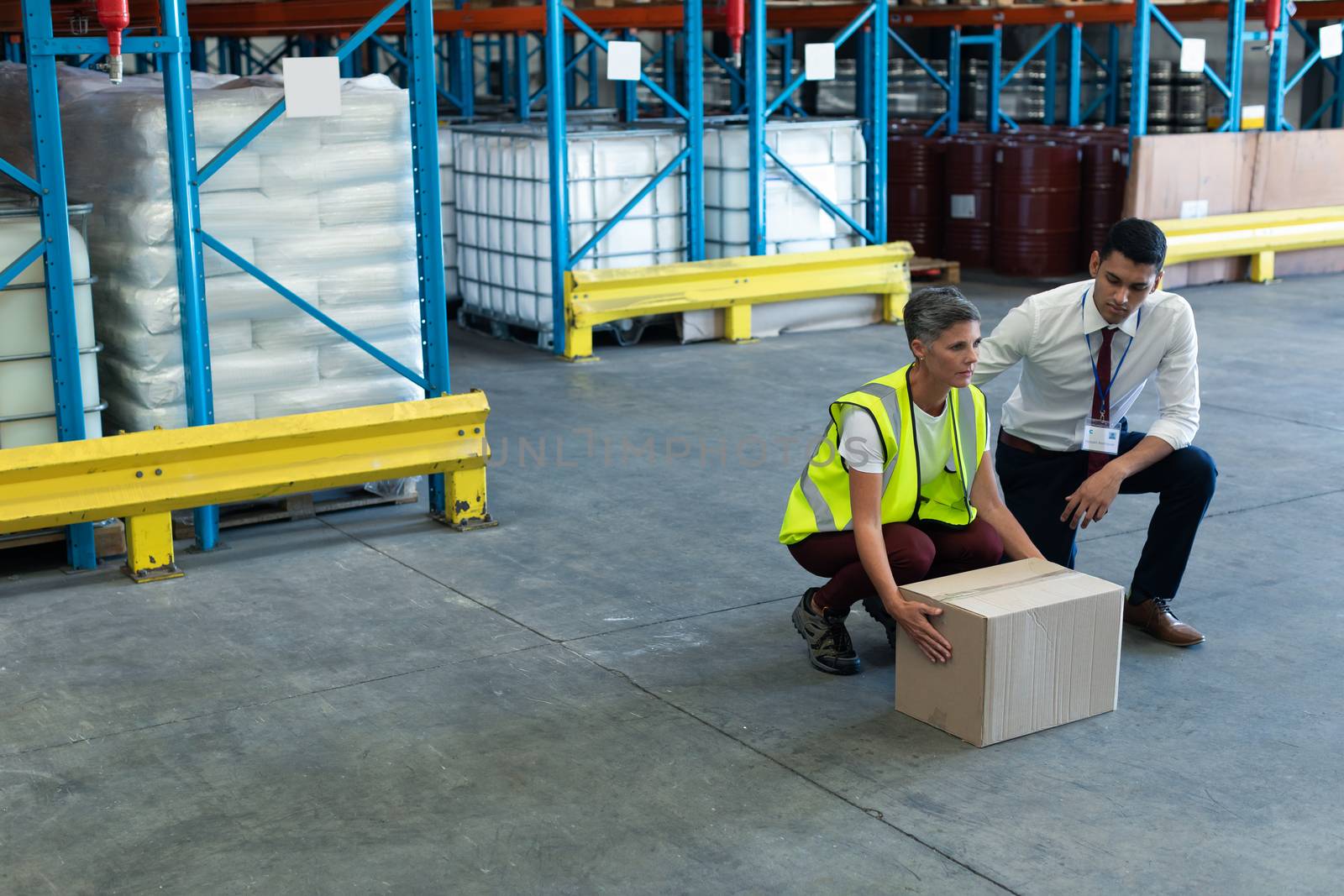 Front view of Young mixed-race male staff giving training to Caucasian female staff in warehouse. This is a freight transportation and distribution warehouse. Industrial and industrial workers concept