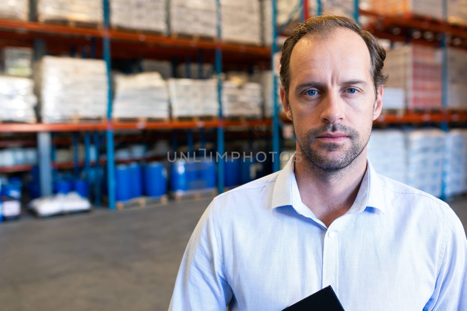 Portrait close-up of handsome Caucasian male supervisor looking at camera in warehouse. This is a freight transportation and distribution warehouse. Industrial and industrial workers concept