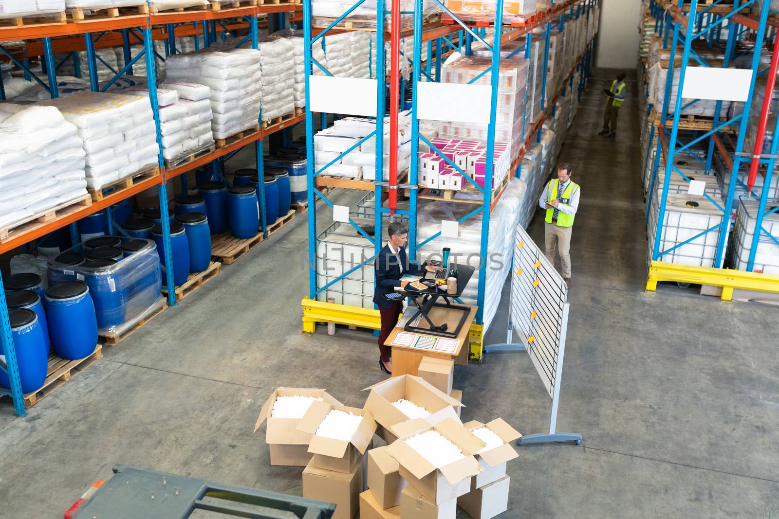 High angle view of mature Caucasian warehouse staff working together in warehouse. This is a freight transportation and distribution warehouse. Industrial and industrial workers concept