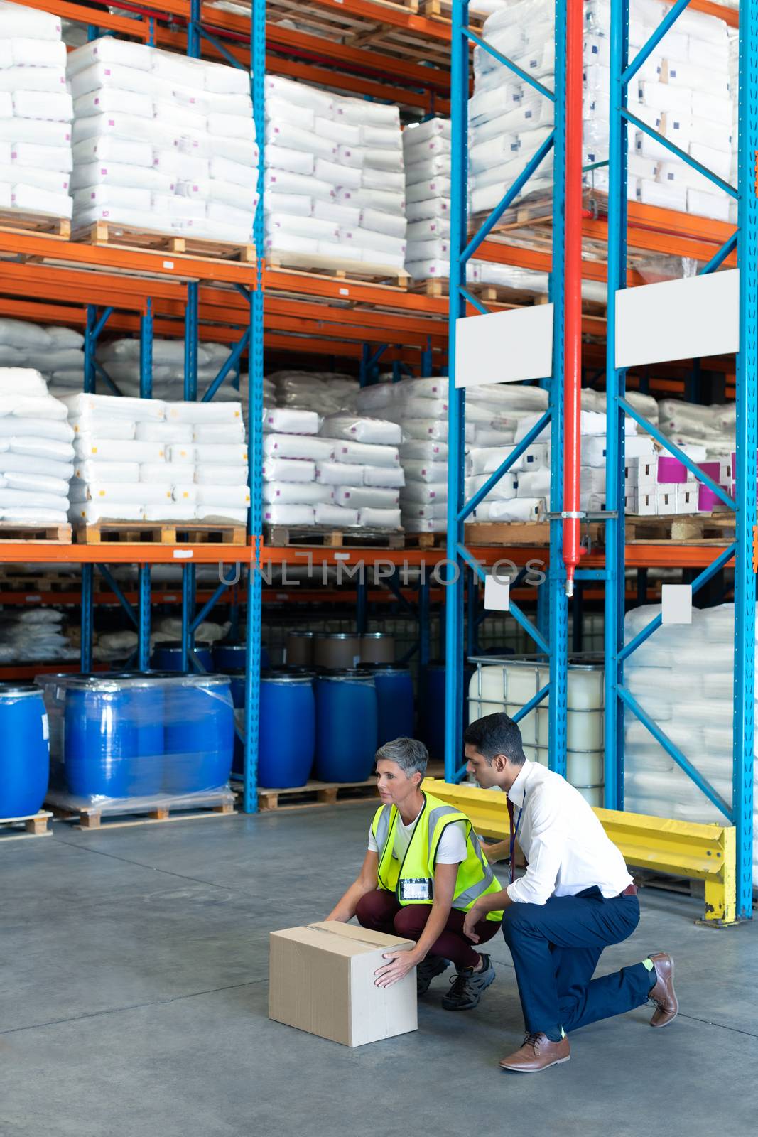Side view of Caucasian Young male staff giving training to Caucasian female staff in warehouse. This is a freight transportation and distribution warehouse. Industrial and industrial workers concept