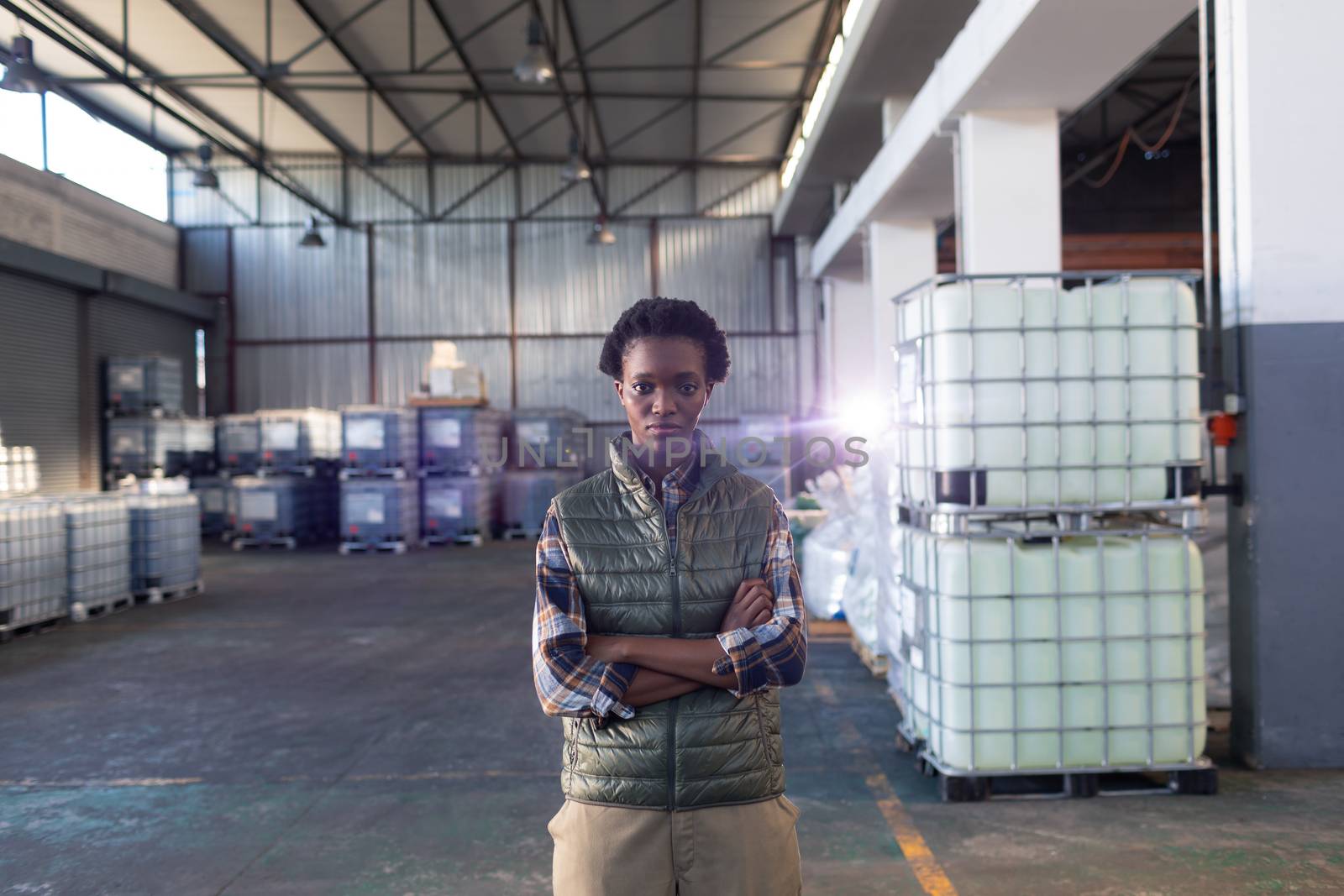 Female staff standing with arms crossed in warehouse by Wavebreakmedia