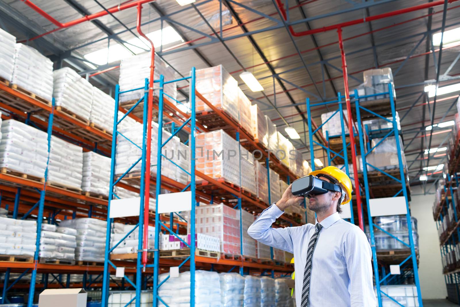 Front view of handsome Caucasian male supervisor using virtual reality headset in warehouse. This is a freight transportation and distribution warehouse. Industrial and industrial workers concept