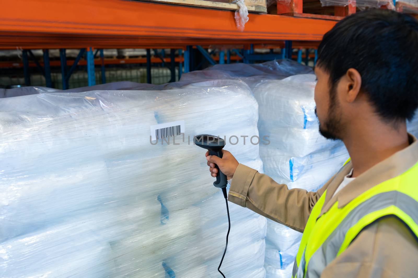 Male worker scanning package with barcode scanner in modern warehouse by Wavebreakmedia